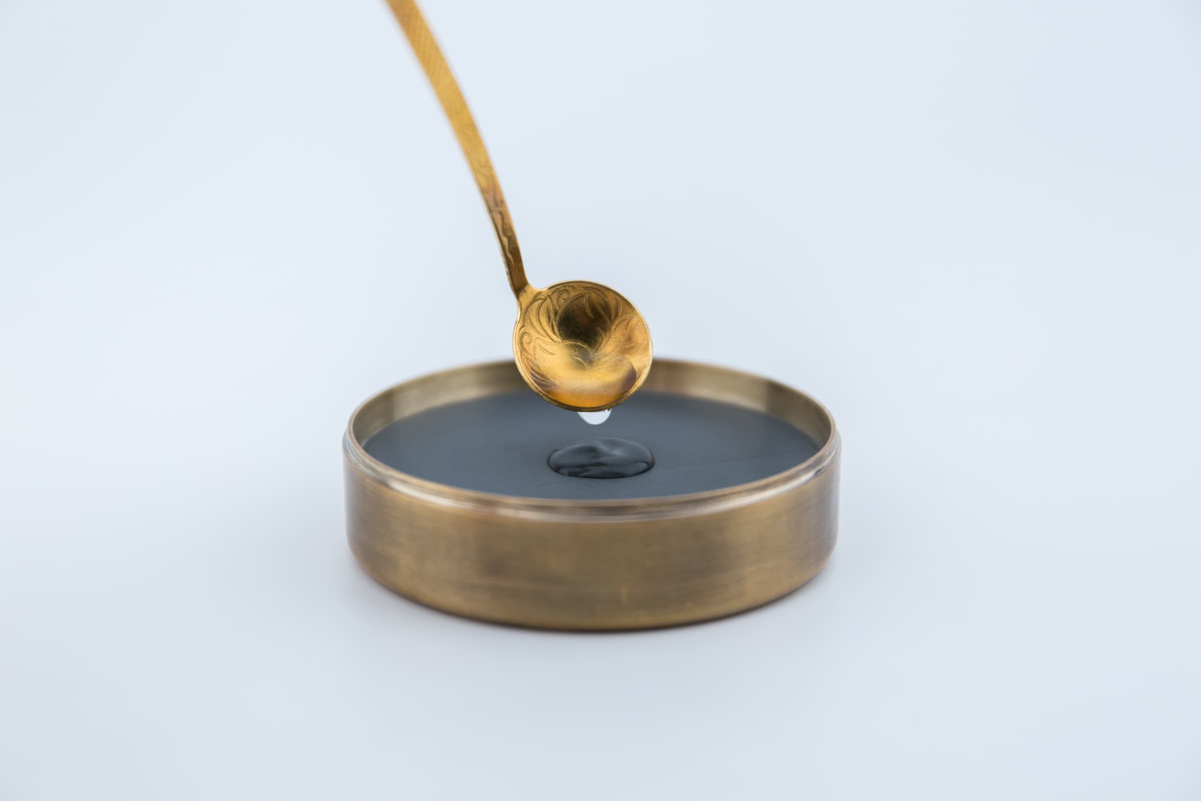 Using the spoon to add water from the pot to the inkstone